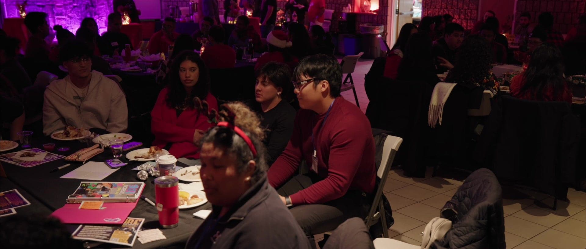 A table mid conversation, plates cleared, the room full behind
